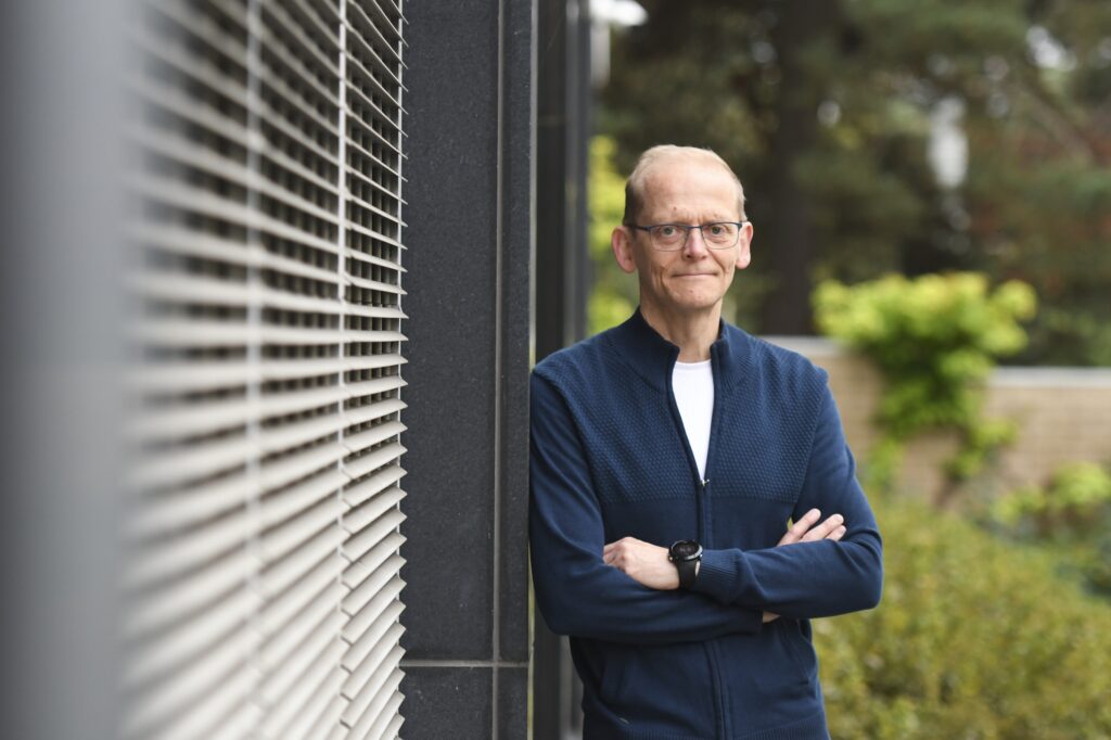 Mikael Sallinen seisoo pihalla rakennuksen vieressä ja katsoo kameraan.