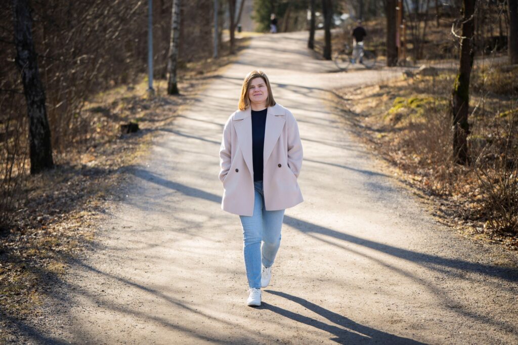Tuija Leskinen kävelee hiekkatietä pitkin ja taustalla näkyy metsää ja pari kuntoilijaa.