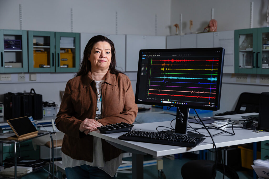 Työterveyslaitoksen (TTL) tutkija Jutta Karkulehto fysiologian laboratoriossa. Vieressä pöydällä on tietokoneen näyttö.