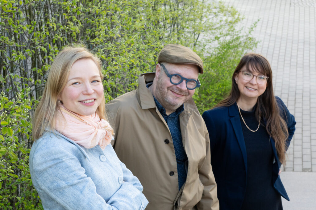 Henkilökuvassa tutkija Emmi Siirtola, professori Jari Stenvall sekä tutkija Sanni Pöntinen. Taustalla näkyy pensaita ja katukivetystä.