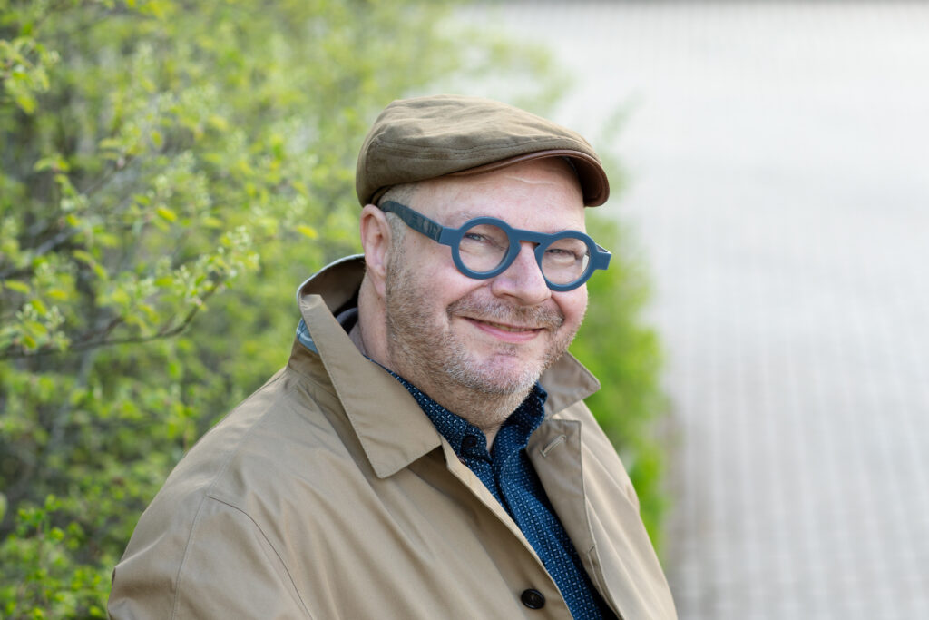 Henkilökuvassa professori Jari Stenvall. Taustalla näkyy pensaita ja katukiveä.
